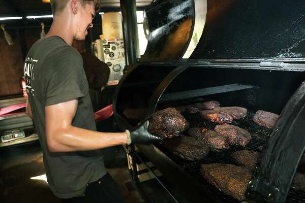 Dusty Dworak, pit hand and slicer at 2M Smokehouse, moves briskets in a custom-made smoker.