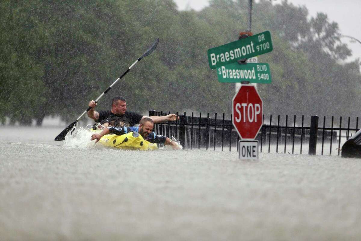 Hilell Tayer and Alex Gonik try to beat the current pushing them down an overflowing Brays Bayou along S. Braeswood in Houston, Texas, Sunday, Aug. 27, 2017. Rescuers answered hundreds of calls for help Sunday as floodwaters from the remnants of Hurricane Harvey climbed high enough to begin filling second-story homes, and authorities urged stranded families to seek refuge on their rooftops.