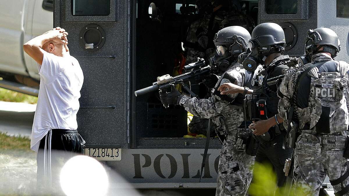 In this photo taken Wednesday, Aug. 28, 2019, officers from the Fairfield Police Department SWAT team remove one of six subjects who had barricaded themselves inside a home in Fairfield, Calif., after agents from the U.S. Secret Service and the U.S. Marshal's Service attempted to serve an arrest warrant. Officials in Northern California say federal agents arrested six people after using tear gas to force them from a Fairfield home during an eight-hour standoff. (Joel Rosenbaum/The Reporter via AP)