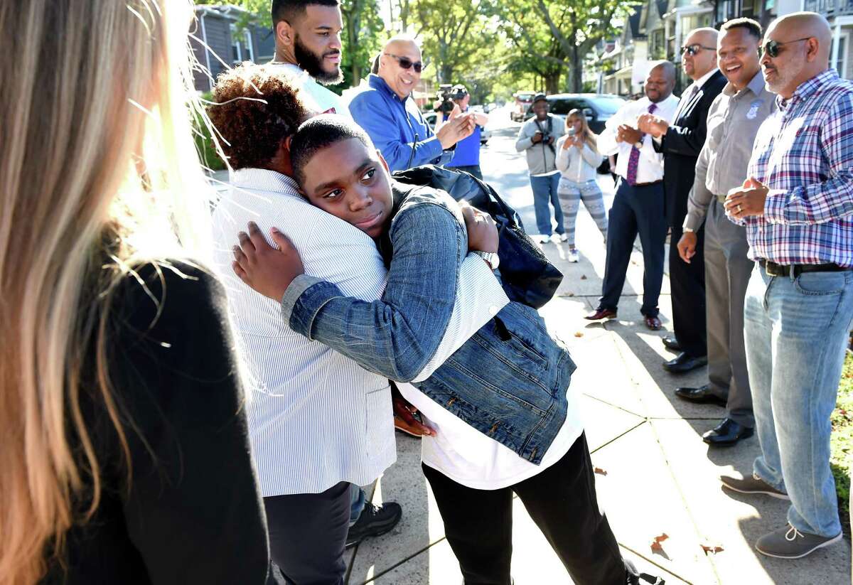 Sixth grader Troy Price, 11, (center) hugs principal Rosalind Garcia on the first day of school at Lincoln Bassett Community School in New Haven as he arrives on August 29, 2019.