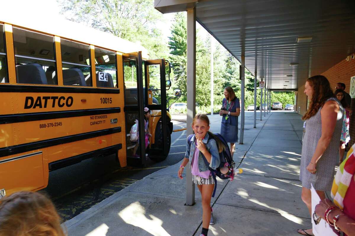 It is a happy recent first day of school at West School in New Canaan, as children walk away from the school bus at the school. This year, students in the town are less likely to ride a bus to a public school in the town if its school district re-opens its buildings, during the coronavirus pandemic, according to a survey.