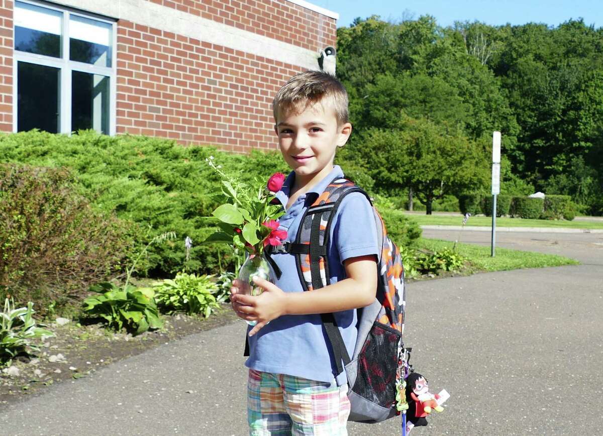 Max Frattaroli, 5, brings roses for his teacher at the school in New Canaan on the first day of school August 29, 2019. He was excited to get back to school because "I get to meet my class," he said. East School’s roof is behind Frattaroli, and has been protecting the school for 25 years.