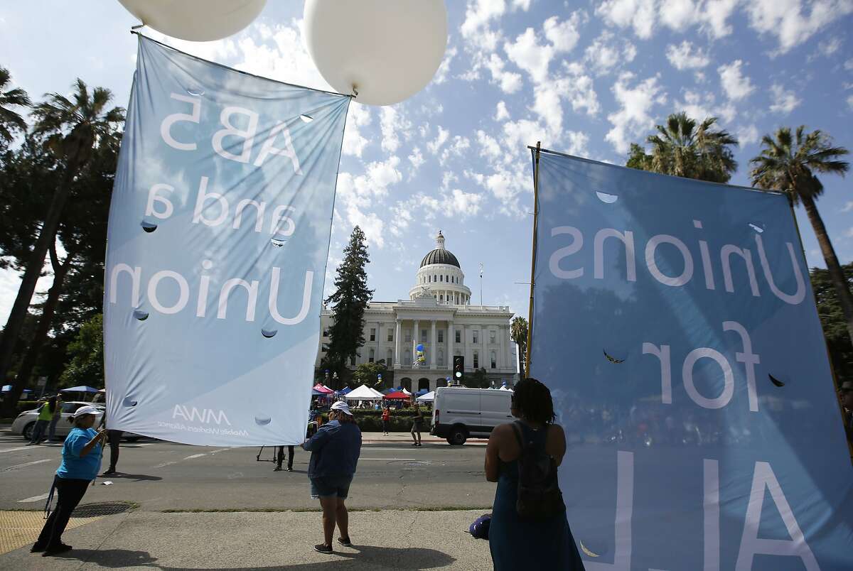 Supporters of a measure to limit when companies can label workers as independent contractors display banners in support of the bill during a rally at the Capitol in Sacramento, Calif., Wednesday, Aug. 28, 2019. If approved by the legislature and signed by Gov. Gavin Newsom, AB5, by Assemblywoman Lorena Gonzalez, D-San Diego, would require companies like Uber and Lyft to treat their drivers like employees. (AP Photo/Rich Pedroncelli)