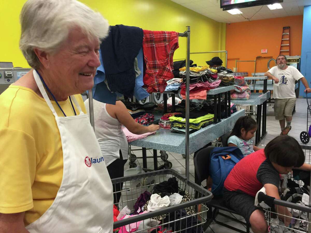 Volunteer Georgia Carrington of Ridgefield, looks on as families enjoy a free visit to the White Street Wash laundromat in Danbury, courtesy of the local Laundry Love initiative.
