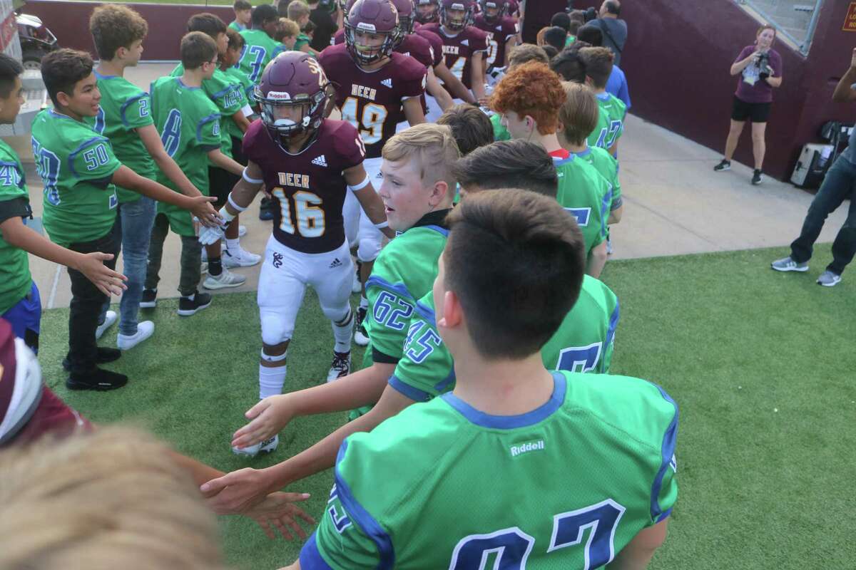 Deer Park's Jesus Solano and Quinton Simons come through a reception line of Fairmont Junior High players before Friday night's game. All of the junior high programs were on hand to help the Deer kick off their season.