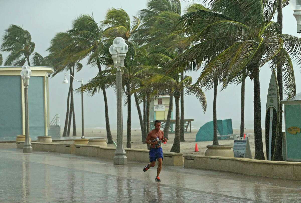 A beachgoer runs under the rain at the Hollywood Beach Broadwalk on Saturday, Aug. 31, 2019 Hollywood, Fla. The latest forecast says Hurricane Dorian is expected to stay just off shore of Florida and skirt the coast of Georgia, with the possibility of landfall still a threat on Wednesday, and then continuing up to South Carolina early Thursday. (David Santiago/Miami Herald via AP)
