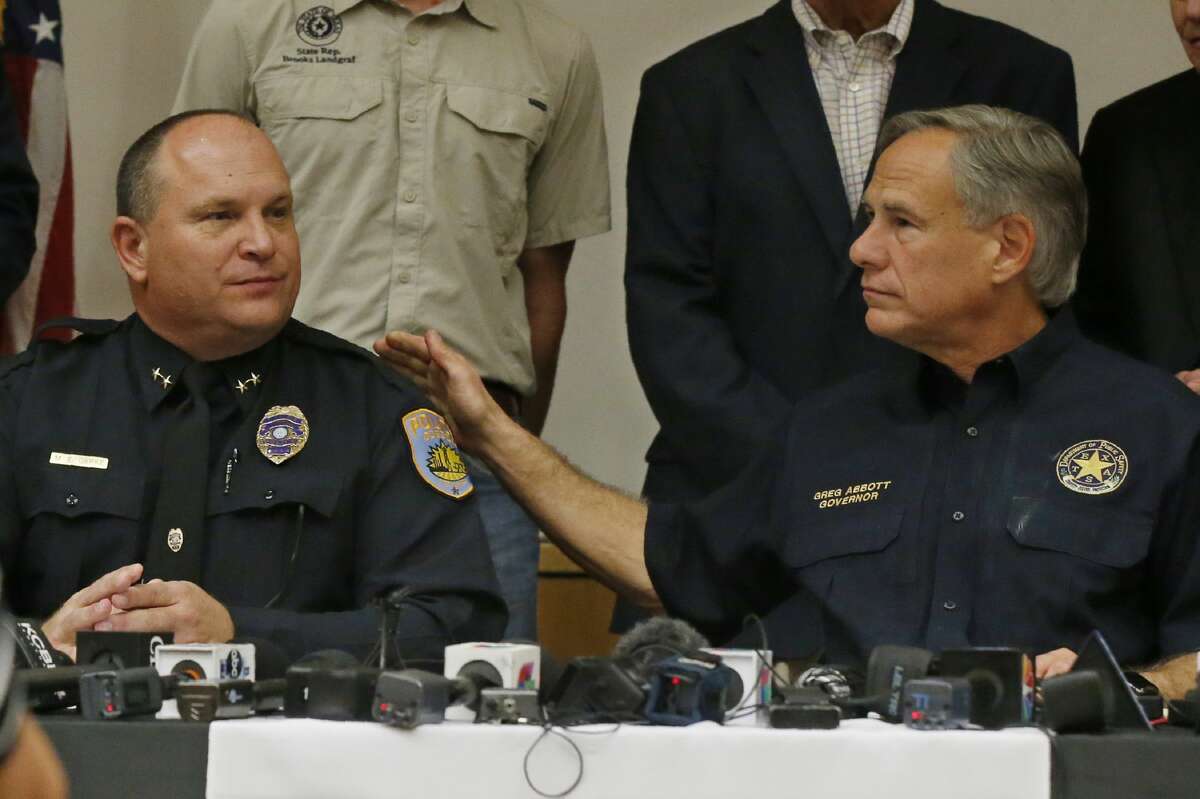 Texas Governor Greg Abbott, right, pats Odessa Police Chief Michael Gerke, left, on the shoulder during a news conference about Saturday's shooting, Sunday, Sept. 1, 2019, in Odessa, Texas. (AP Photo/Sue Ogrocki)