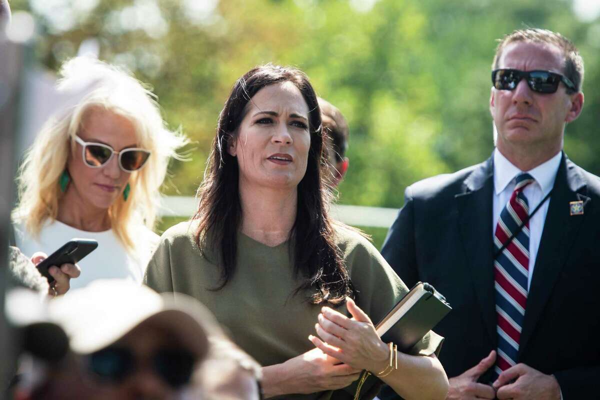 White House press secretary Stephanie Grisham listens as President Donald Trump stops to talk to reporters and members of the media at the White House on Aug. 21, 2019.