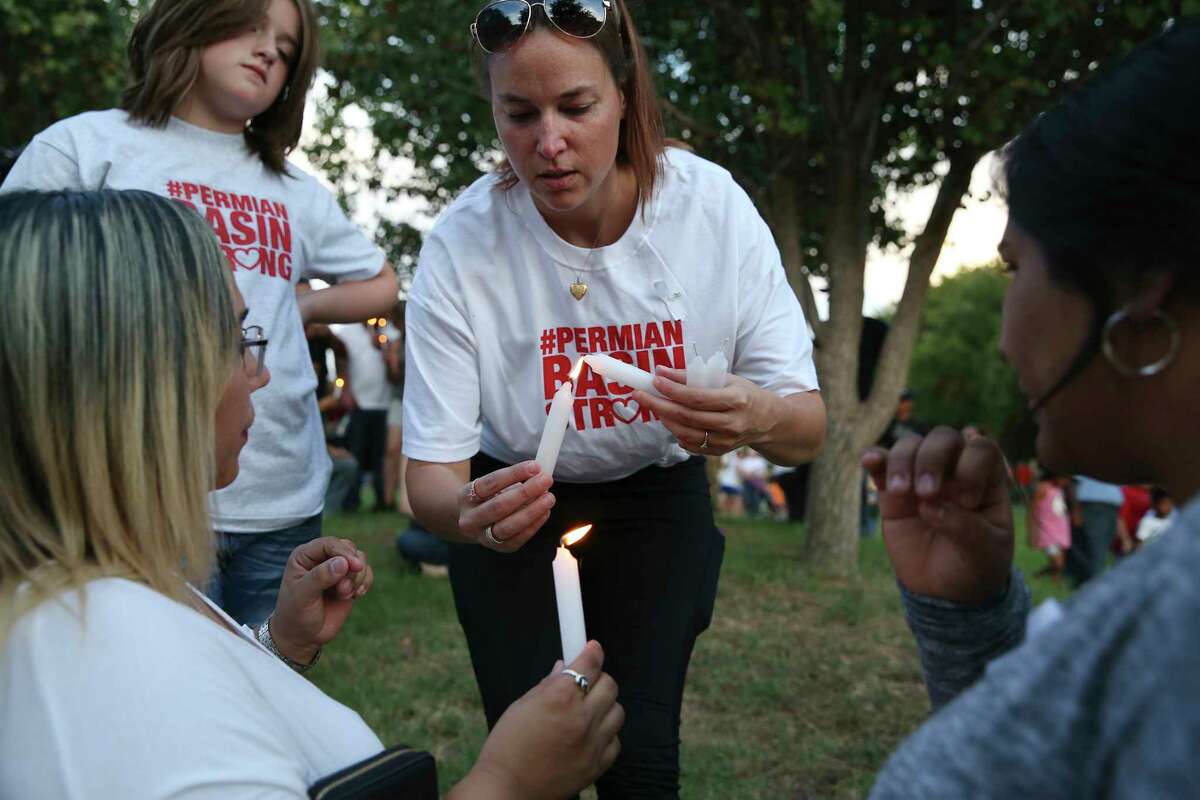 Christinah Fischer, center, lights candles after a vigil at the University of Texas of the Permian Basin in Odessa, Texas on Sunday, Sept. 1, 2019. The vigil was for the victims of Saturday's mass shooting. Seth Aaron Ator, 36, of Odessa, is suspected of killing seven people an injuring 19 in a shooting spree on Saturday. With her is daughter, Naomi Brammer, left.