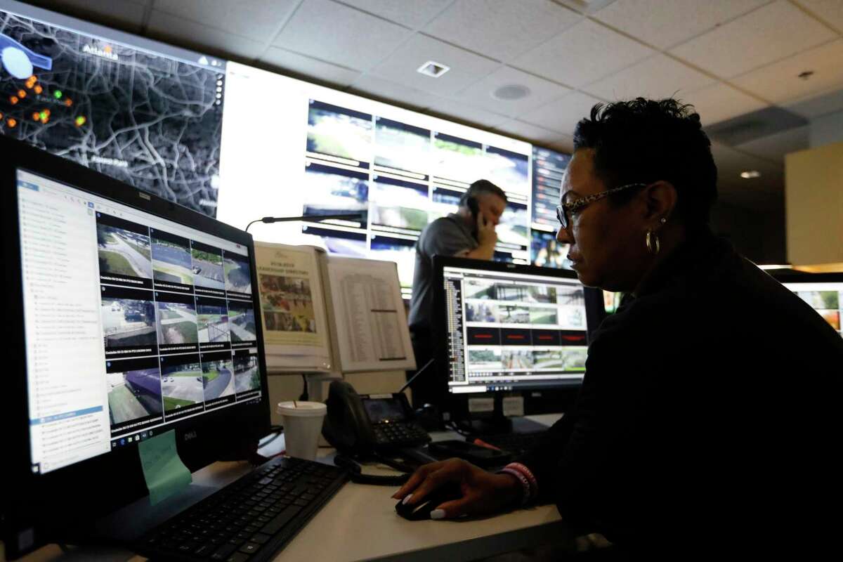 In this July 30, 2019, photo, Sandra Swint, right, campus security associate for Fulton County School District and Paul Hildreth, background, the districtas emergency operations coordinator, work in the emergency operations center at the Fulton County Schools Administration Center in Atlanta. Artificial Intelligence is transforming surveillance cameras from passive sentries into active observers that can immediately spot a gunman, alert retailers when someone is shoplifting and help police quickly find suspects. Schools, such as the Fulton County School District, are among the most enthusiastic adopters of the technology. (AP Photo/Cody Jackson)