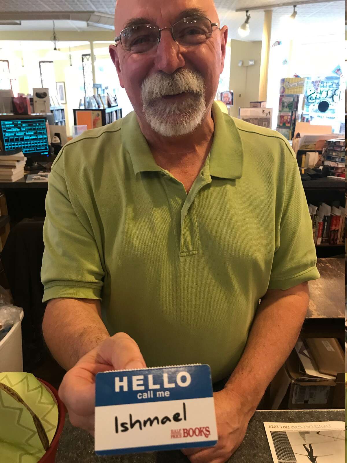 Stanley Hadsell with an Ishmael name tag a friend gave him, which he keeps next to his computer at Market Block Books in Troy (Paul Grondahl / Times Union)
