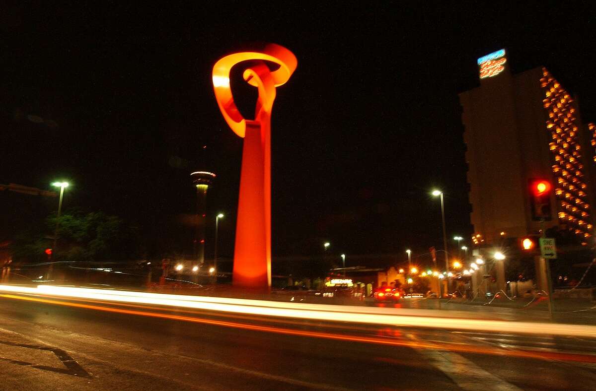 Downtown traffic streaks past the “Torch of Friendship,” the monumental sculpture by Sebastian that was donated to the city in 2002.