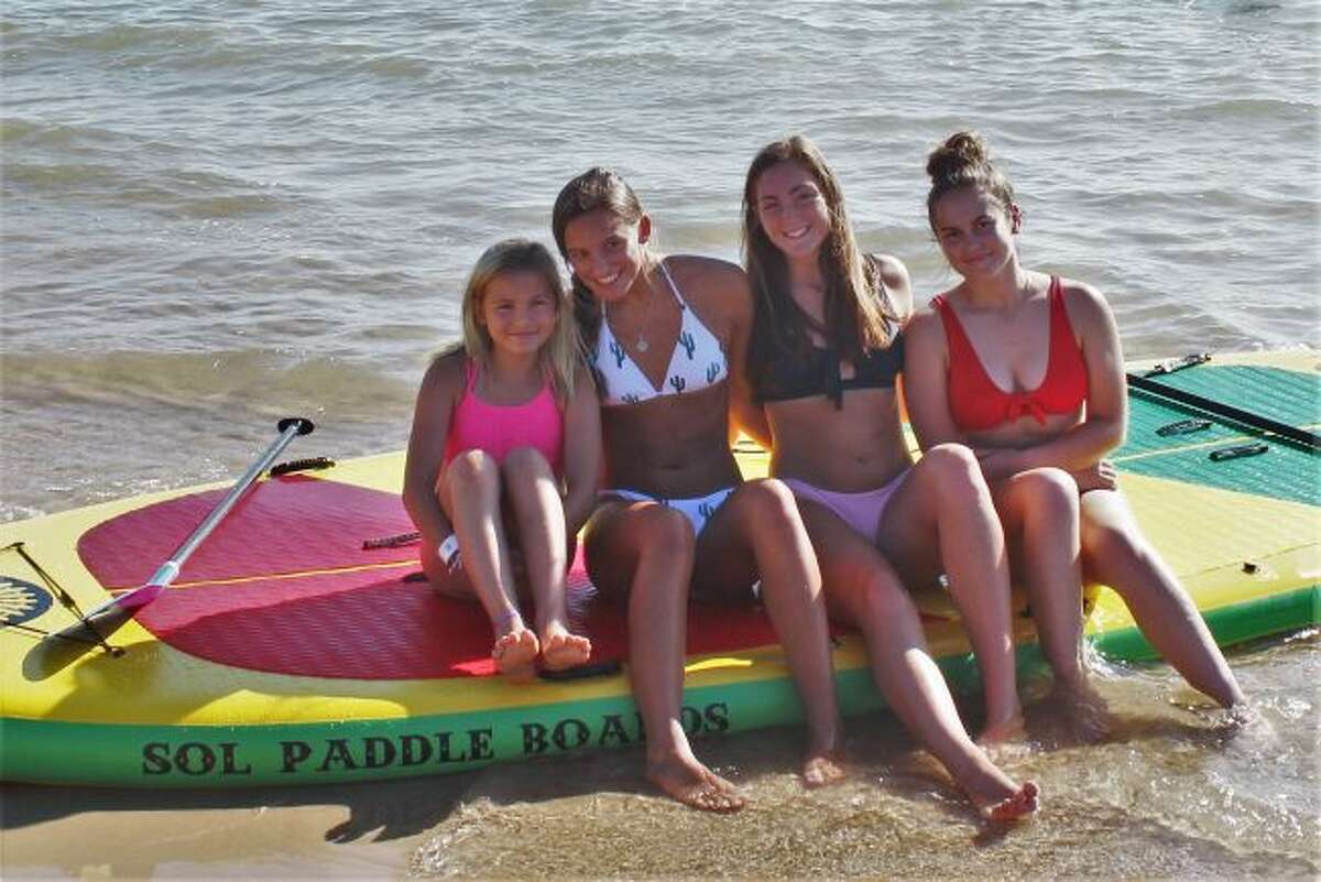 Graeleigh Jensen, of Manistee, prepares to enjoy a paddle boarding adventure with Frankfort National Honor Society members Reagan Thorr, Emily Loney and Cora Scott. (Robert Myers/Pioneer News Network)