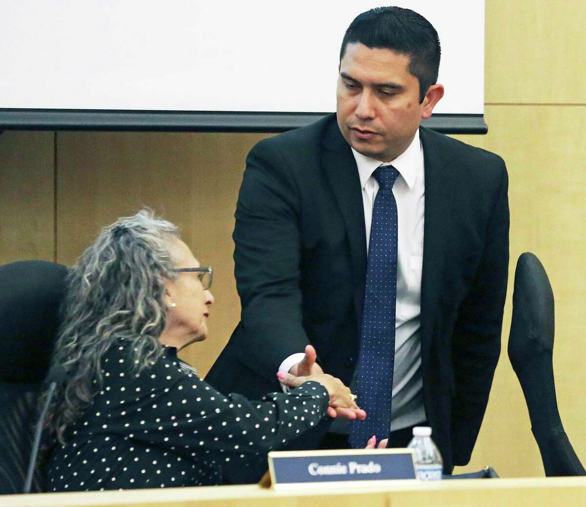 Former South San ISD superintendent Alex Flores shakes hands with Board President Connie Prado just before taking a buyout. South San has been plagued by governance issues, but consolidation isn’t the solution. School finance reform is a better solution.