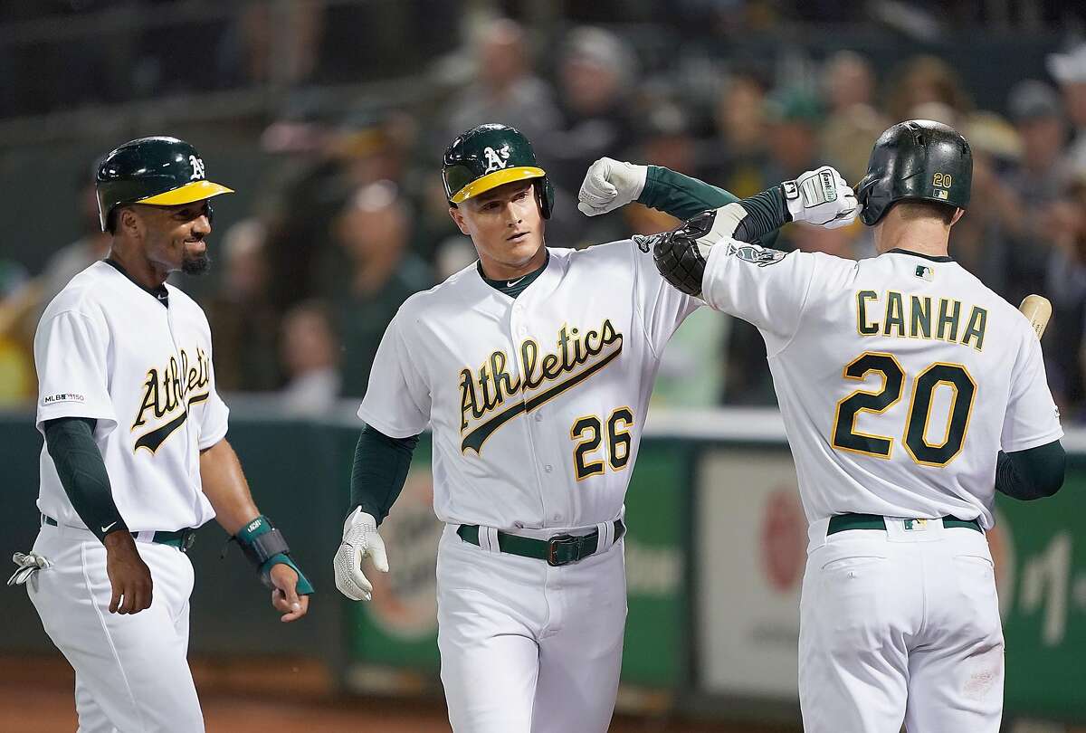 OAKLAND, CA - SEPTEMBER 03: Matt Chapman #26 of the Oakland Athletics is congratulated by Marcus Semien #10 and Mark Canha #20 after Chapman hit a three-run home run against the Los Angeles Angels of Anaheim in the bottom of the third inning at Ring Central Coliseum on September 3, 2019 in Oakland, California. (Photo by Thearon W. Henderson/Getty Images)