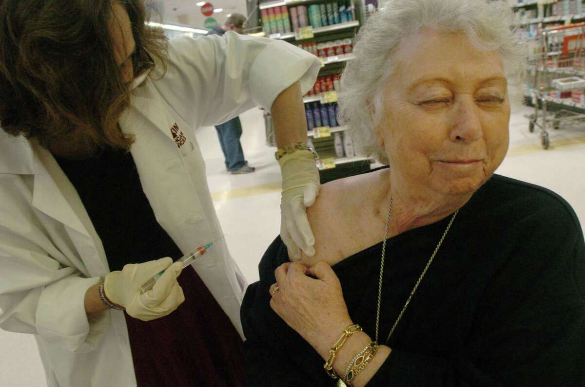 Marylin Schectman, of Stamford, can't bear to look as Jo Anne Fortmann prepares to adminster a flu shot at the Stop & Shop Pharmacy on Bedford St. /Staff photo