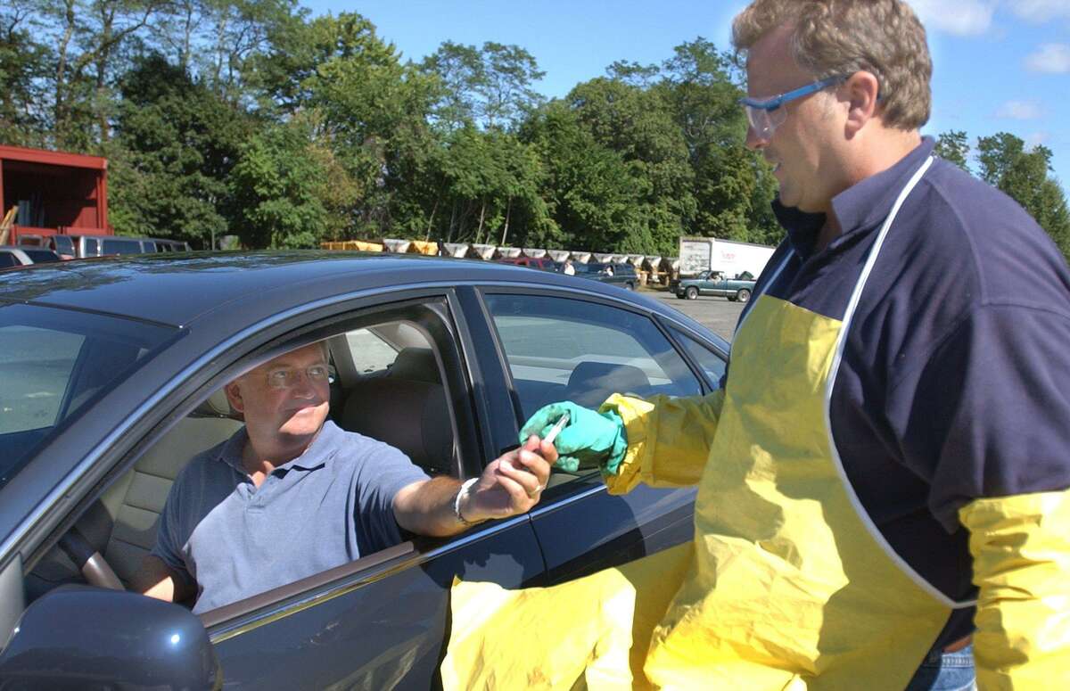 Ron Kanode of Ridgefield hands a mercury themometer to hazardous wastes worker, Mike Corrado. ARea residents dumped off all manner of household debris yesterday at the Danbury Publicv Works Department annual Household Hazardous Waste Collection Day.