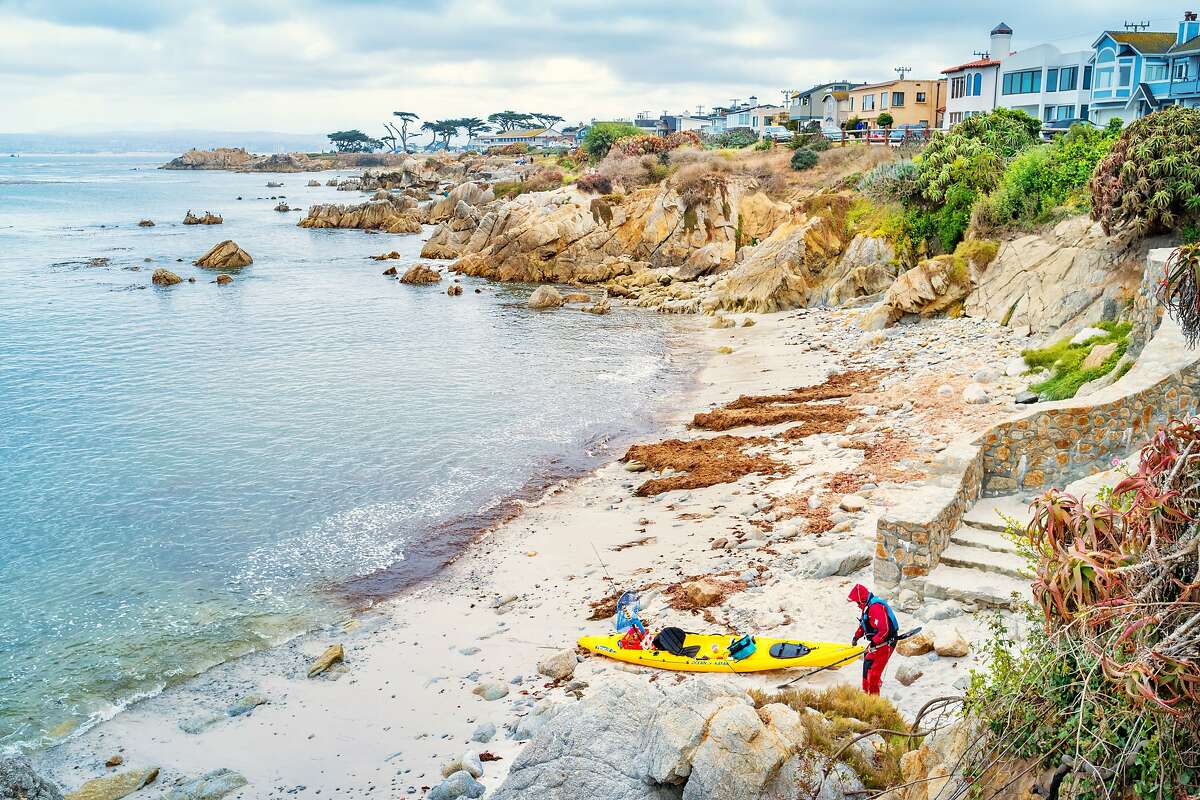 Person returns from a kayak trip at Pacific Grove with Lovers Point in the background in Monterey, California.
