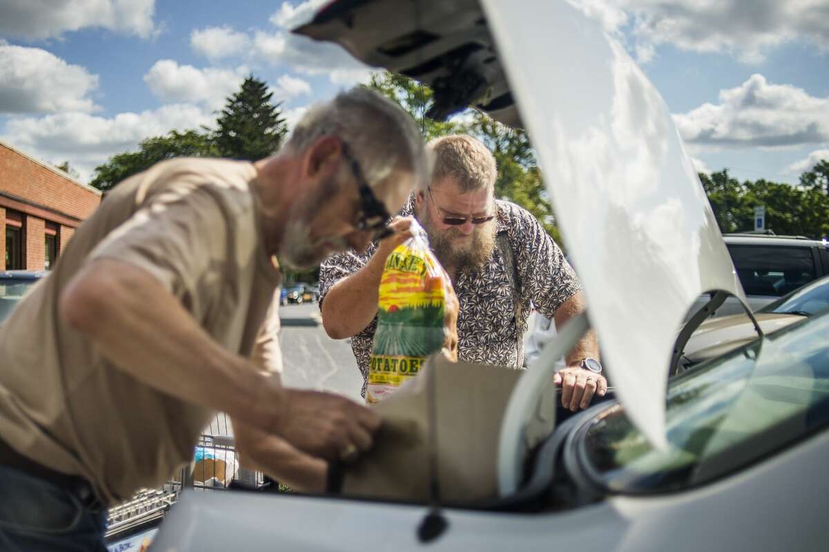 Volunteers John Burke of Midland, left, and Marv Lynch of Midland, right, help to load food items donated by the Midland County Emergency Food Pantry Network into vehicles during the annual Project Community Connect event Thursday, Sept. 5, 2019 at Trinity Lutheran Church. (Katy Kildee/kkildee@mdn.net)