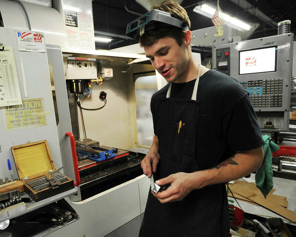 CNC machinist Chris Heun, of Stratford, a recent graduate of Housatonic Community College's Advanced Manufacturing Training program, deburrs a part coming out of a CNC mill at Schwerdtle Stamp at 41 Benham Avenue in Bridgeport, Conn. on Thursday, June 13, 2013.