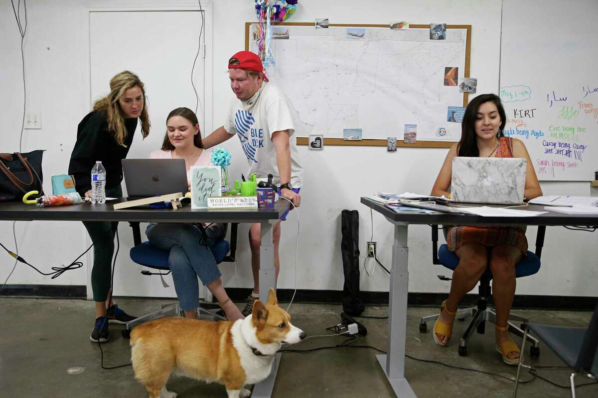 Blue Duck CEO Eric Bell looks over ideas last May with his employees, including from left, Elizabeth Lyons Houston, then the vice-president and chief marketing officer, Sarah Washington and Magda Gonzalez-Jimenez. With them is Bell’s Corgi, Rooney. Blue Duck is a local company that offers scooter rentals in San Antonio.