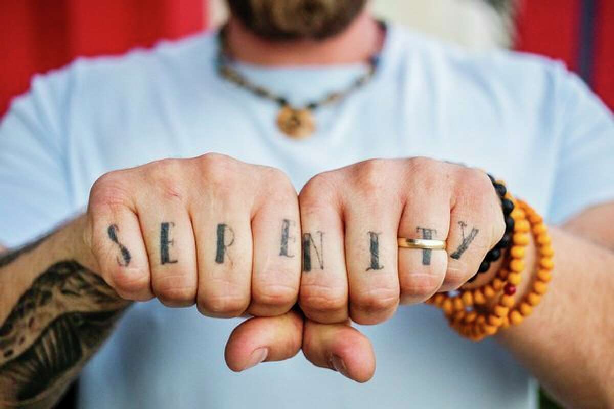 Zachary Brewer displays his knuckle tattoo, which reads "serenity," as he poses for a portrait Thursday in Bay City. (Katy Kildee/kkildee@mdn.net)