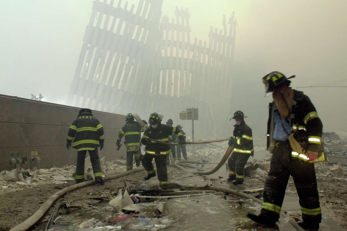 FILE - In this Sept. 11, 2001 file photo, firefighters work beneath the destroyed mullions, the vertical struts which once faced the outer walls of the World Trade Center towers, after a terrorist attack on the twin towers in New York. New research released on Friday, Sept. 6, 2019 suggests firefighters who arrived early or spent more time at the World Trade Center site after the 9/11 attacks seem to have a greater risk of developing heart problems than those who came later and stayed less. (AP Photo/Mark Lennihan)