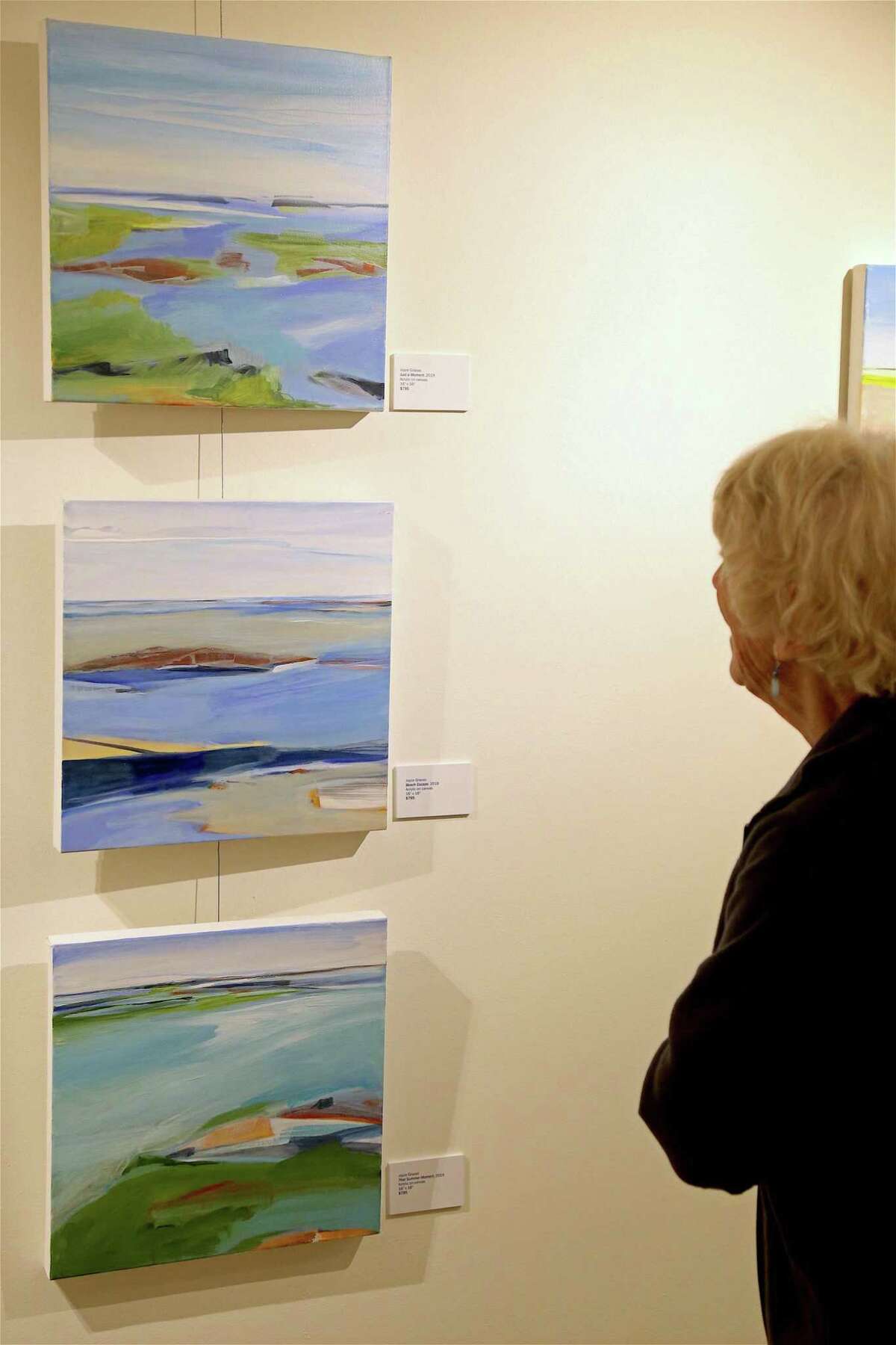 Jane Bowler of Fairfield studies some work at the opening reception for the art show "Coastal Expressions" by Joyce Grasso at the Pequot Library on Thursday, Sept. 5, 2019, in Fairfield, Conn.