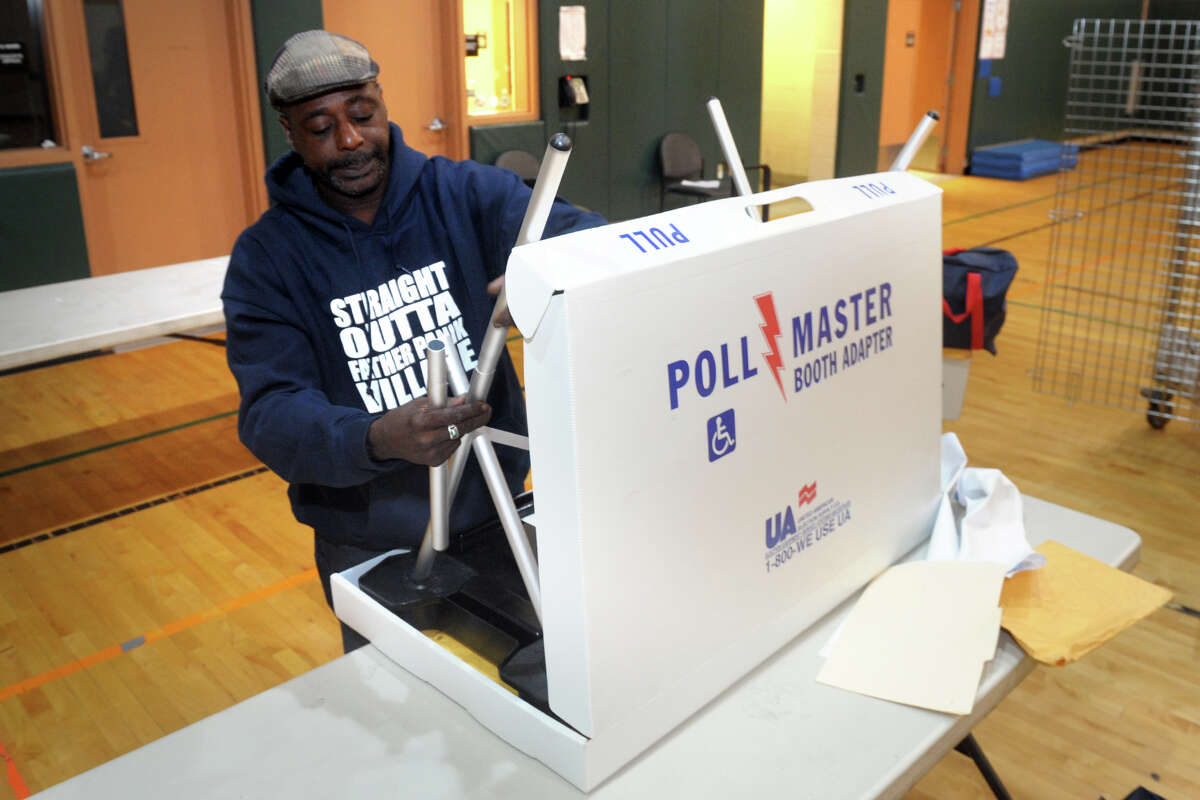 Everett Taylor prepares a polling booth in preparation for Tuesday’s primary election at Barnum School, in Bridgeport, Conn. Sept. 9, 2019.