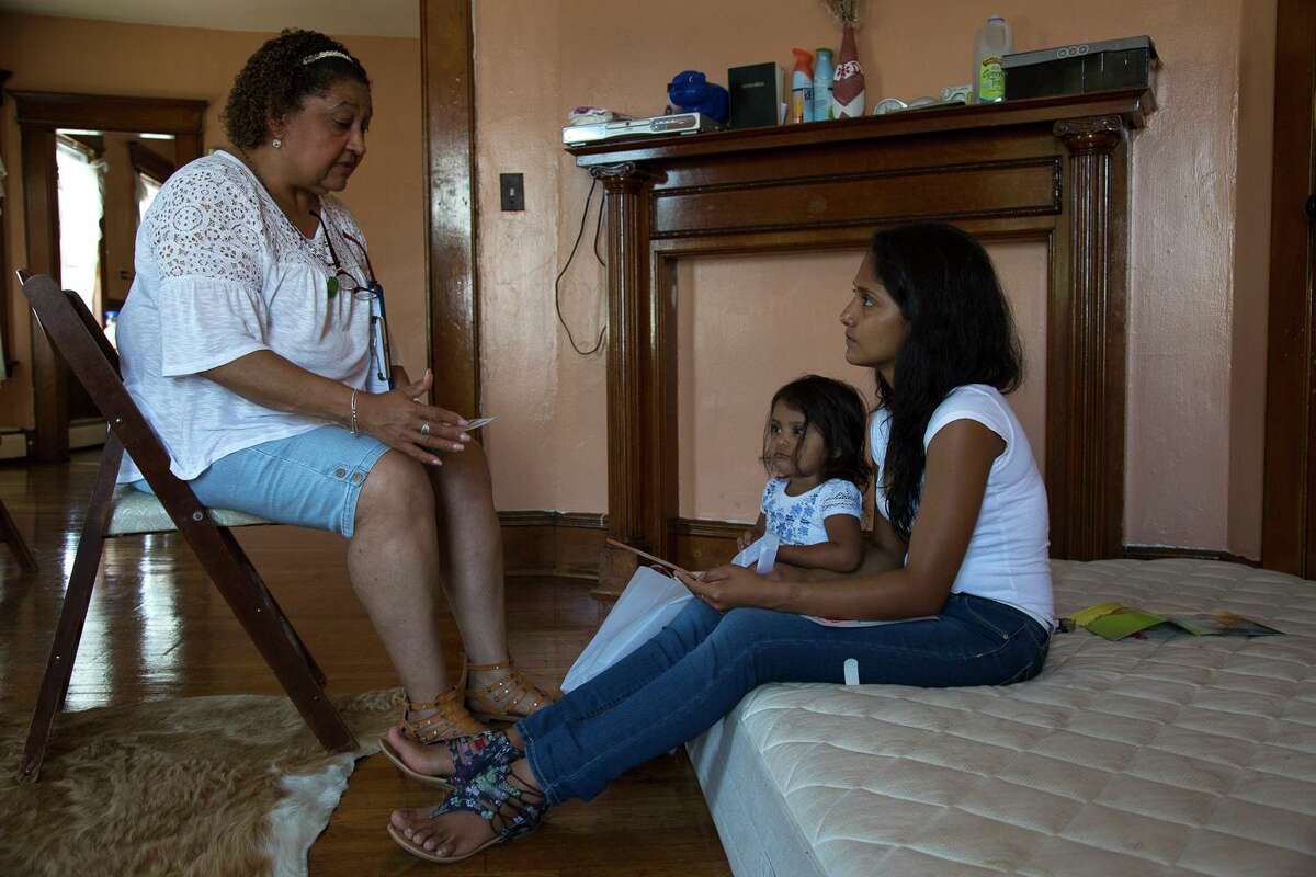 A community health worker in Bridgeport, Conn., discusses vaccines with a client. These workers reach those who cannot afford care.