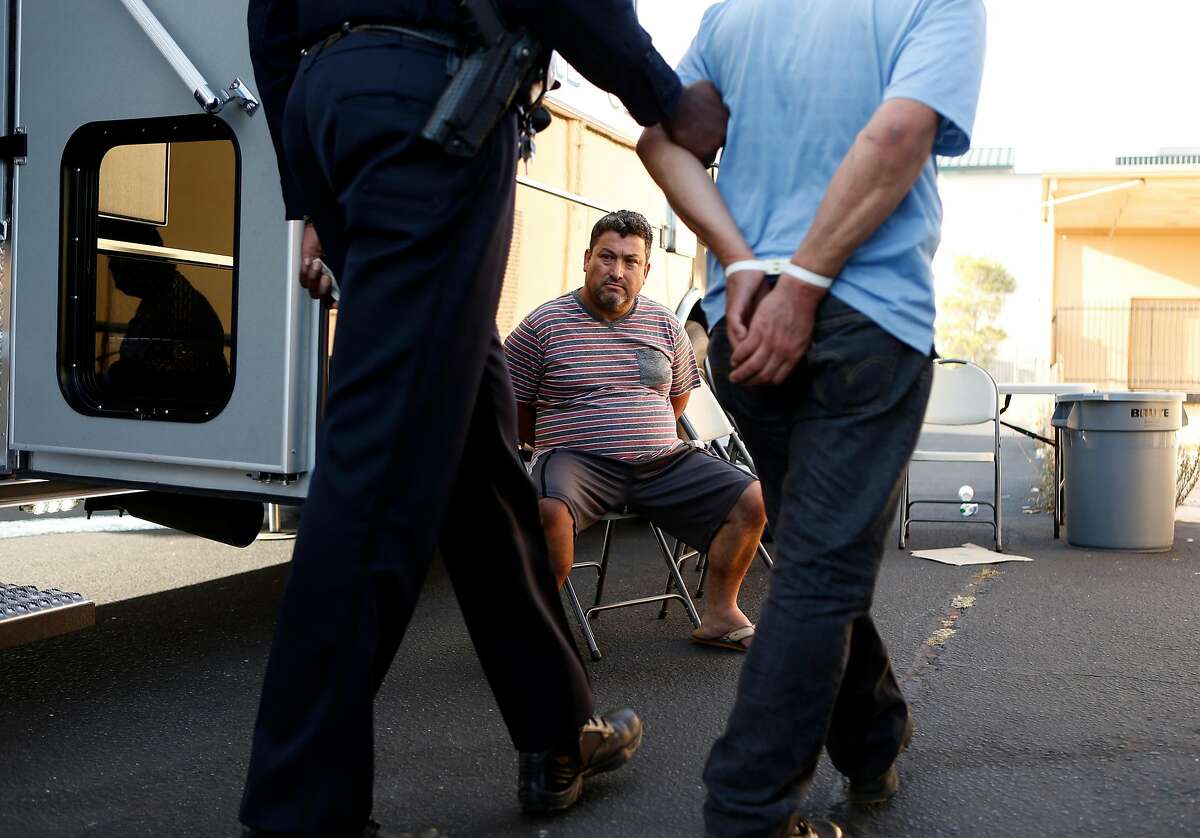 After being arrested on suspicion of soliciting an undercover officer posing as a prostitute, Gabriel Moreno sits at the Richmond Police Department command center on 22nd Street as fellow arrestee Rogelio Gutierrez arrives during a sting operation in Richmond, Calif. on Thursday, September 4, 2014.