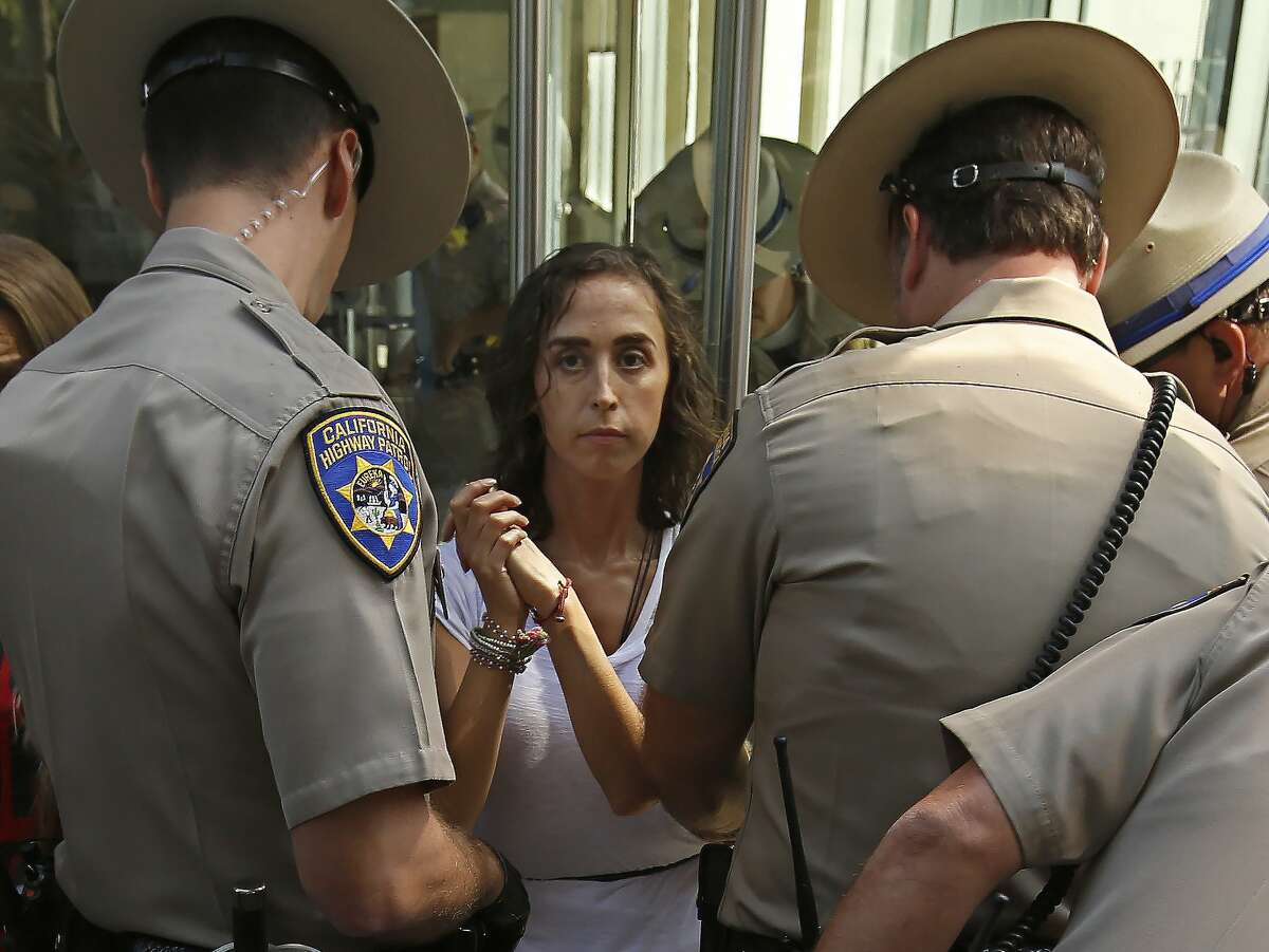 California Highway Patrol officers take into custody an opponent of recently passed legislation to tighten the rules on giving exemptions for vaccinations, after she cabled herself to the doors of the state Capitol in Sacramento, Calif., Monday, Sept. 9, 2019. The state Assembly approved the companion bill, Monday, with changes demanded by Gov Gavin Newsom as a condition of signing the controversial vaccine bill SB276 which was passed by the Legislature last week.(AP Photo/Rich Pedroncelli)