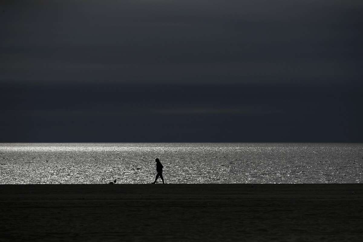 A person strolls along the beach as the Pacific Ocean glitters in the sun Wednesday, Feb. 27, 2019, in the Venice Beach section of Los Angeles. (AP Photo/Jae C. Hong)