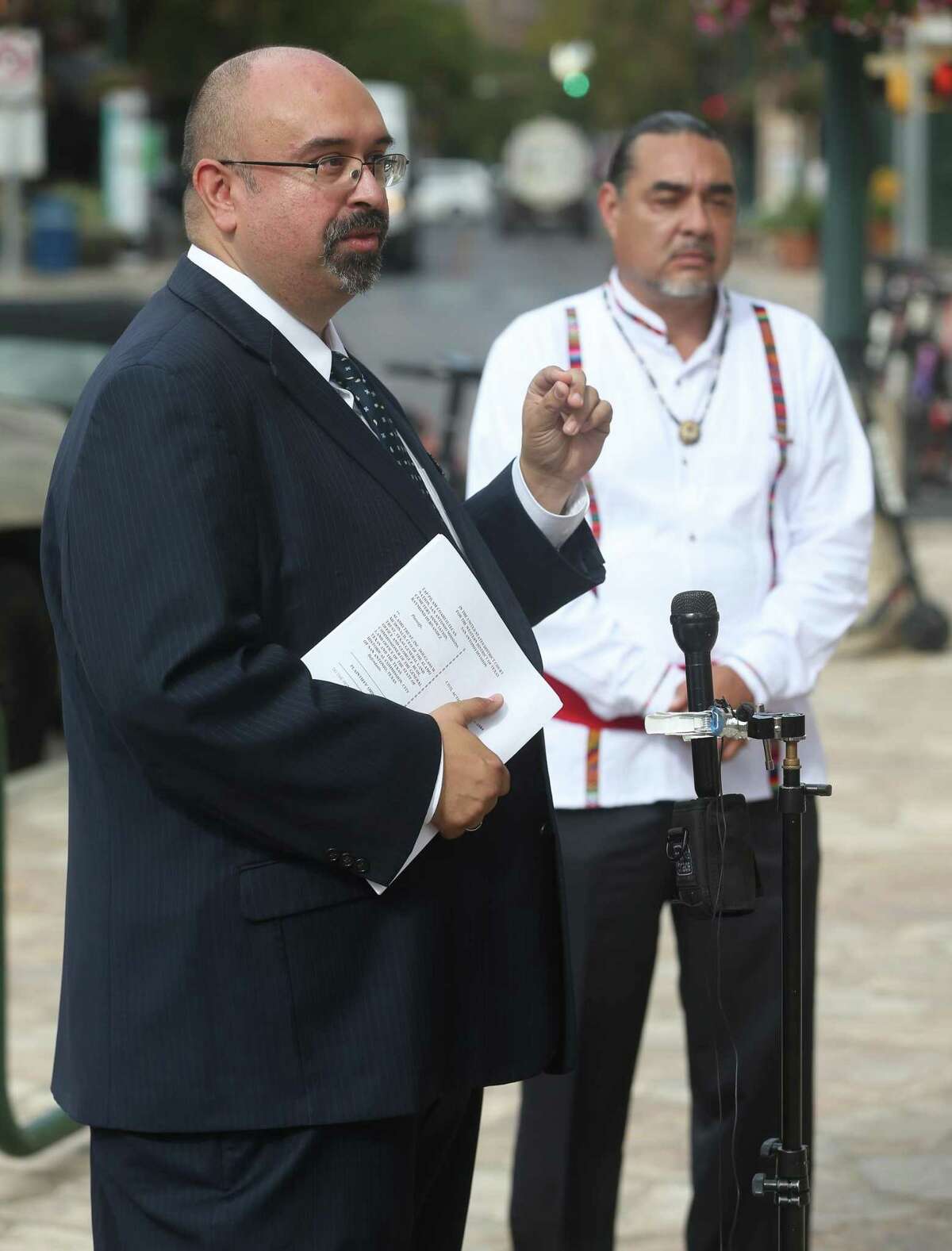 Attorney Art Martinez de Vara, left, speaks to reporters Tuesday in front of the Hipolito F. Garcia Federal Building and U.S. Courthouse across the street from the Alamo. Ramon Vasquez, executive member of the Tap Pilam Coahuiltecan Nation, stands at right. The Native American group, whose members are lineal descendants of the missions, filed a federal lawsuit Tuesday in conjunction with the San Antonio Missions Cemetery Association and Raymond Hernandez against the city of San Antonio, the Texas General Land Office and two other parties to ensure lineal descendants rights are protected and regulatory processes are followed.