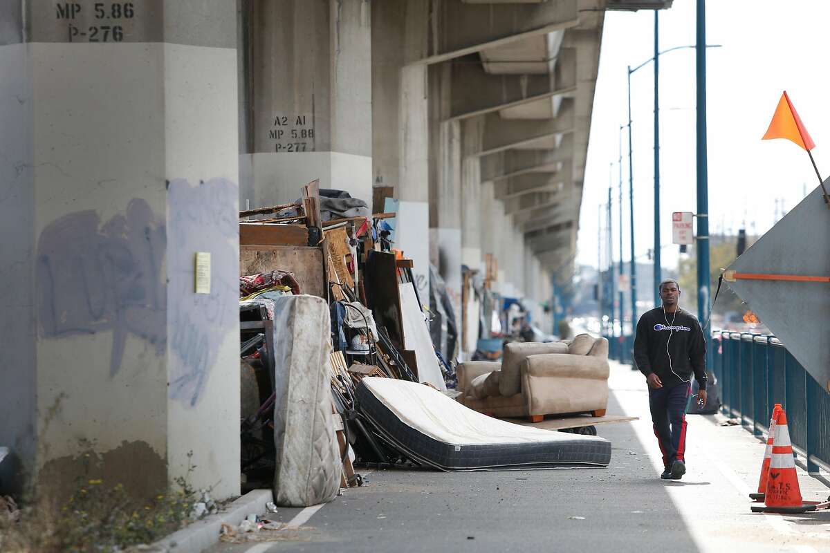Joevaughn Norris of Oakland walks past makeshift structures people built and live in along San Leandro Avenue on Friday, September 6, 2019 in Oakland, CA. Oakland Public Works Department is requiring structures in a homeless encampment along San Leandro Avenue to be dissembled and removed by September 11, 2019 when the encampment will be temporarily closed for a full cleaning.