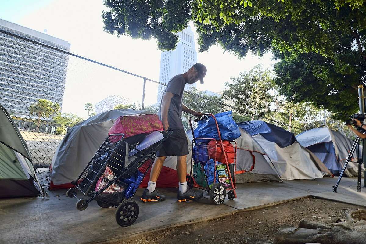 A homeless man moves his belongings from a street near Los Angeles City Hall as crews prepared to clean the area.