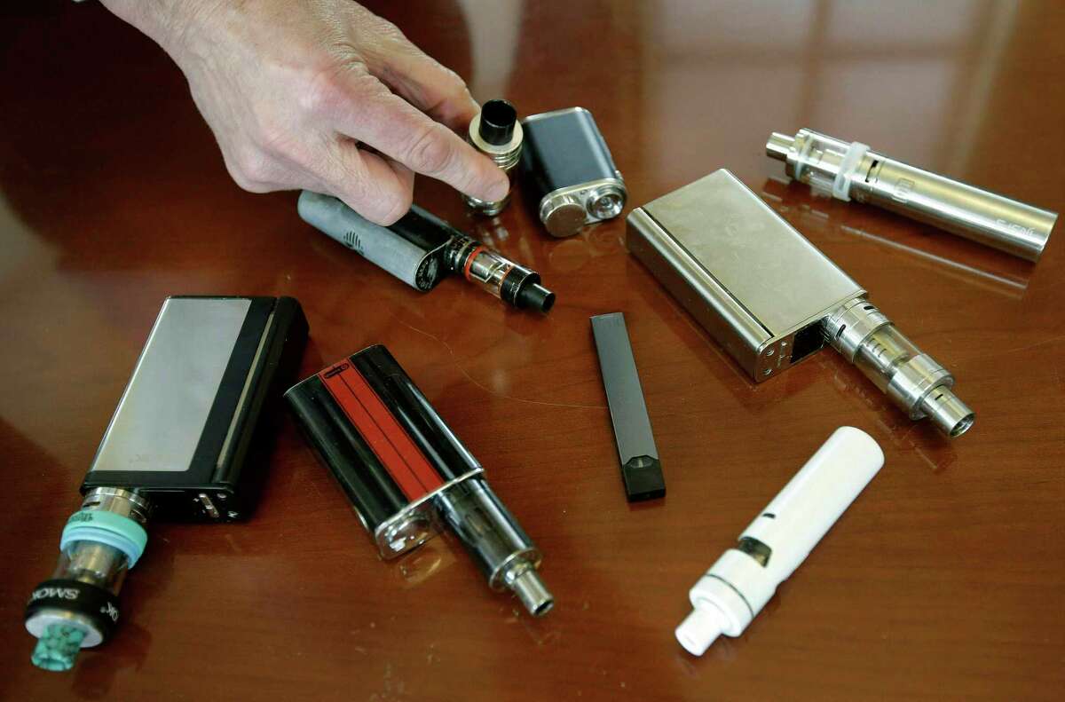 FILE - In this April 10, 2018, file photo, a high school principal displays vaping devices that were confiscated from students in such places as restrooms or hallways at the school in Massachusetts. On Wednesday, April 3, 2019, the U.S. Food and Drug Administration said it has not established a direct connection between vaping and seizures but is seeking more information. Regulators noted that seizures and convulsions are a known side effect of nicotine poisoning. (AP Photo/Steven Senne, File)