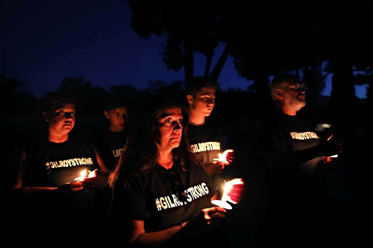Liz Pieteroniski, third from left, stands with her daughter, Kimberly Farley, grandson Ryan Farley, 13, grandson, Ritchie Farley, 16, and husband Glenn Pieteroniski, during a candlelight vigil at El Roble Park in Gilroy, Calif., on Tuesday, July 30, 2019. The event, hosted by Idle Hands Studio and Gilroy Gold, was held two days following a mass shooting during the Gilroy Garlic Festival. Liz Pieteroniski left Christmas Hill Park thirty minutes before the shooting began.