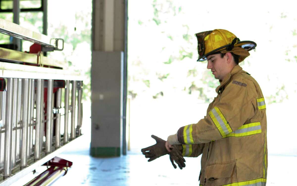 Firefighter Lane Fajkus puts on his gloves before working with the ladders on a fire truck Friday, September 6, 2019 at Conroe Fire Department Station 1 in Conroe.