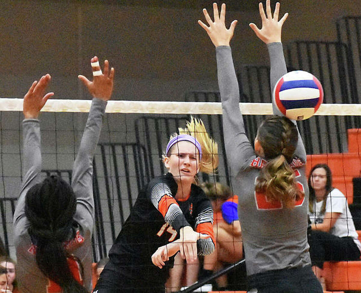 Edwardsville’s Maddie Isringhausen (middle) gets a kill through the block put up by Alton’s Brooke Wolff (right) and Renee Raglin on Tuesday night at Lucco-Jackson Gym in Edwardsville.