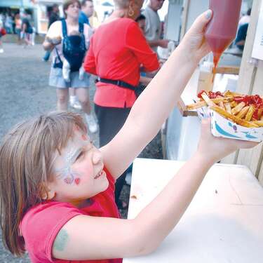 Samantha Seco reaches up for a squirt of ketchup on her french fries during the Durham Fair in this archive photograph.