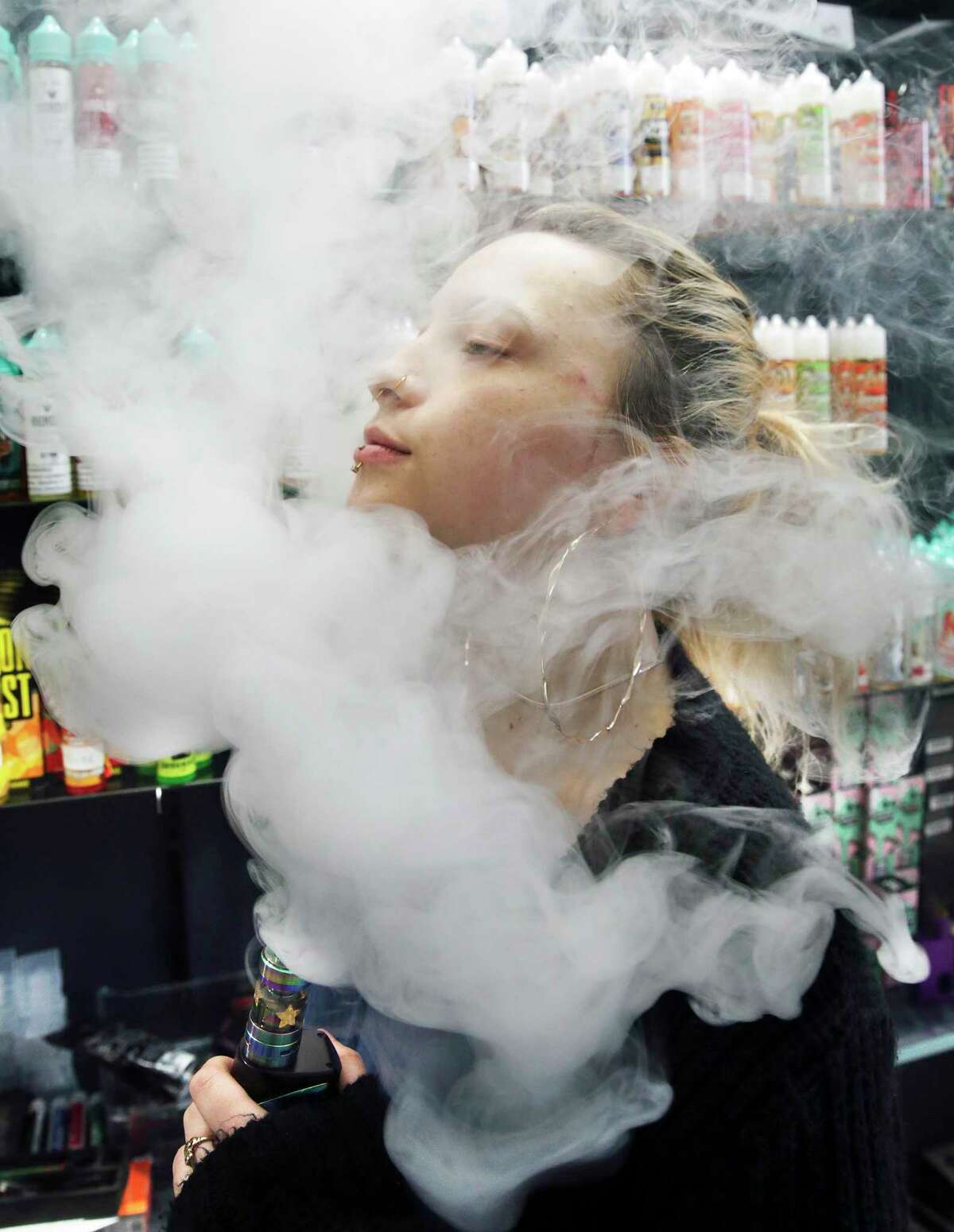 Claire Collingwood is surrounded in a cloud of vapor as she exhales after using a vaping device.