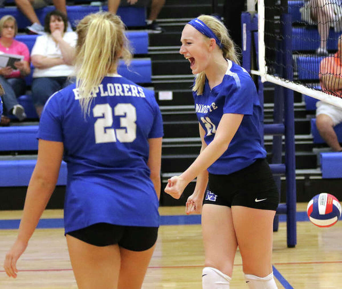 Marquette Catholic’s Emma Menke (right) celebrates a her point off a block with Rae Ezell (23) during a Roxana Tourney three-set loss to Jersey last month in Roxana. The teams met again Wednesday night at Marquette, with the Explorers winning in three sets to hand Jersey its first defeat.