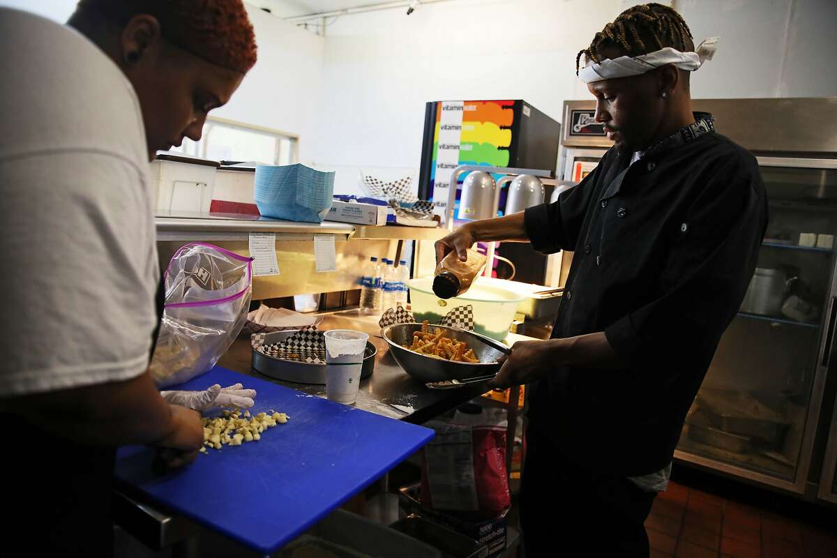 Rianna Armstead, 25, cuts garlic as her brother Rashad Armstead, 31, seasons French fries while they work in the kitchen at Grammie's Down-Home Chicken in Oakland, Calif., on Friday, August 2, 2019.