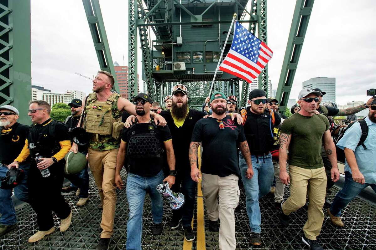 Members of the Proud Boys and other right-wing demonstrators march across the Hawthorne Bridge during an "End Domestic Terrorism" rally in Portland, Ore., on Saturday, Aug. 17, 2019. The group includes organizer Joe Biggs, in green hat, and Proud Boys Chairman Enrique Tarrio, holding megaphone. (AP Photo/Noah Berger)