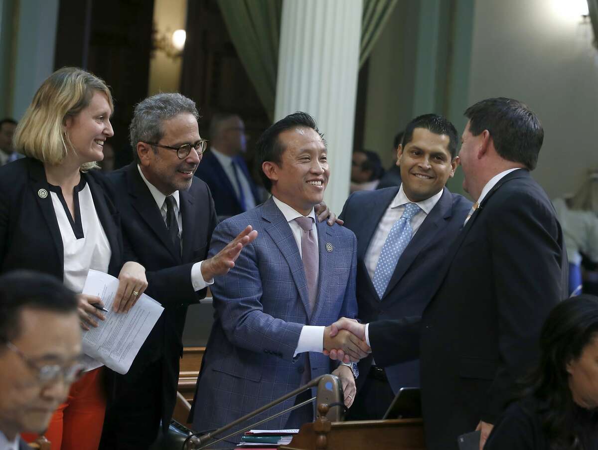 Assemblyman David Chiu,D-San Francisco, center, is congratulated by Assemblyman Timothy Grayson, D-Concord, right, after his measure to cap rent increases was approved by the Assembly in Sacramento, Calif., on Wednesday, Sept. 11, 2019. The bill now goes to Gov. Gavin Newsom. Joining in the celebration are Democratic Assembly members Buffy Wicks, of Oakland, left, Richard Bloom, of Santa Monica, second from left, and Miguel Santiago, of Los Angeles, fourth from left. (AP Photo/Rich Pedroncelli)