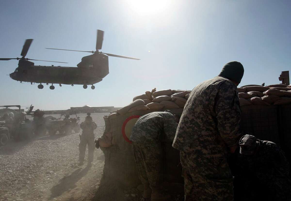 Members of Texas Army National Guard’s Agribusiness Development Team 2 cover up from flying dirt as a CH-47 Chinook helicopter lands at Forward Operating Base Ghazni in this 2009 file photo.