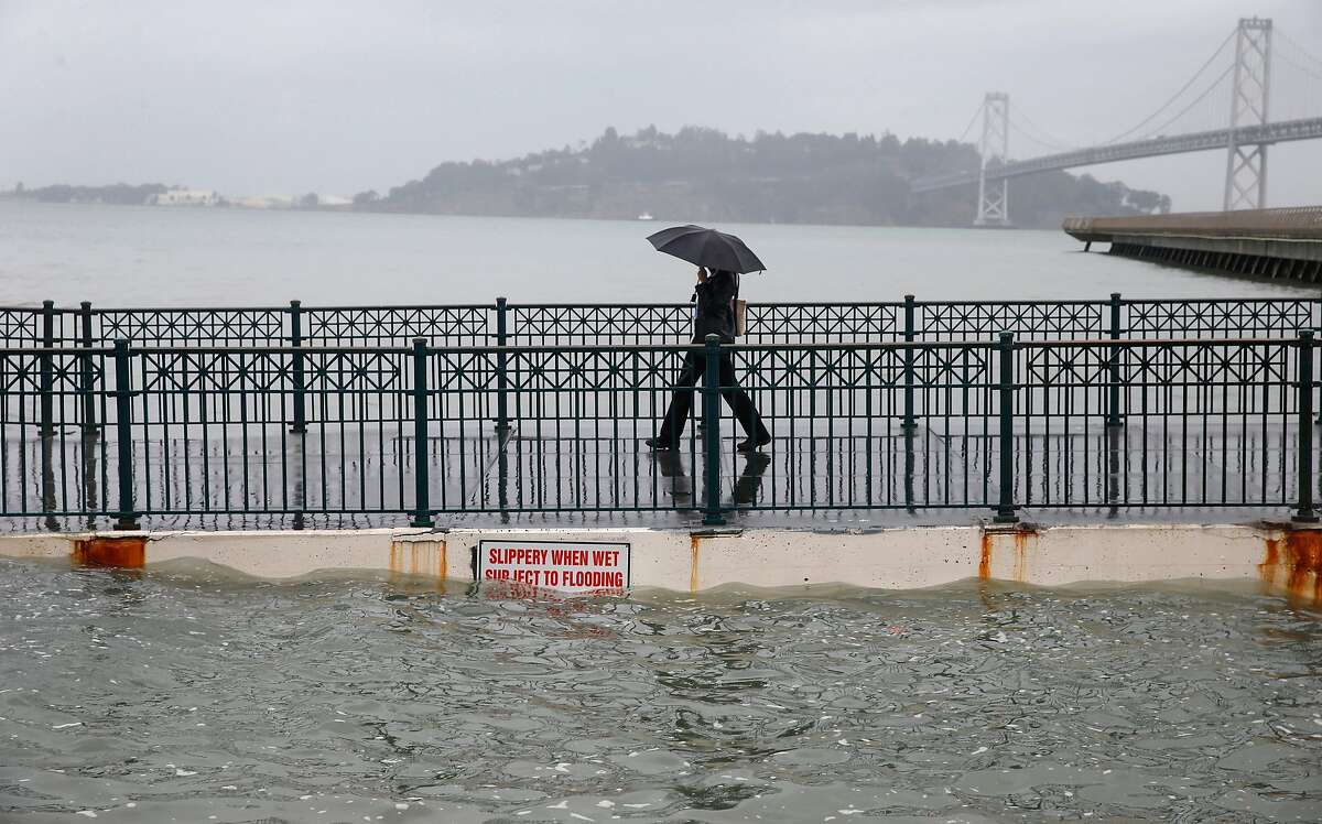 Luna Taylor walks off of Pier 14 during the peak of the high tide along the Embarcadero in San Francisco, Calif. on Tuesday, Nov. 24, 2015. King tide conditions are causing higher than usual water levels.