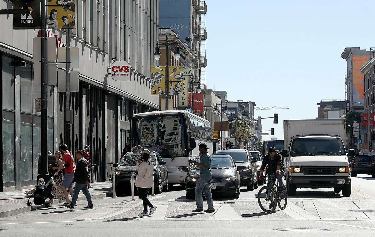 Pedestrians cross on 6th Street at Market Street looking south on Monday, Oct. 15, 2018, in San Francisco, Calif. The SFMTA Board will vote Tuesday on a plan to remove one southbound traffic lane from Sixth Street, a measure to boost safety on a roadway where a pedestrian gets hit by a car about every 16 days.