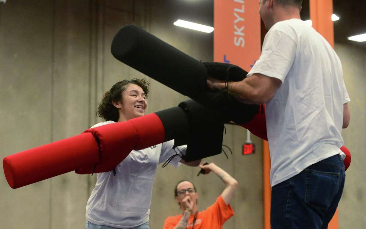 Norwalk police officer Gabriel DeMott, right, and members of the youth group under the umbrella of Juvenile Review Board, including Nayeli Rivera, participate in activities at Sky Zone as part of a mentoring program between police and kids.